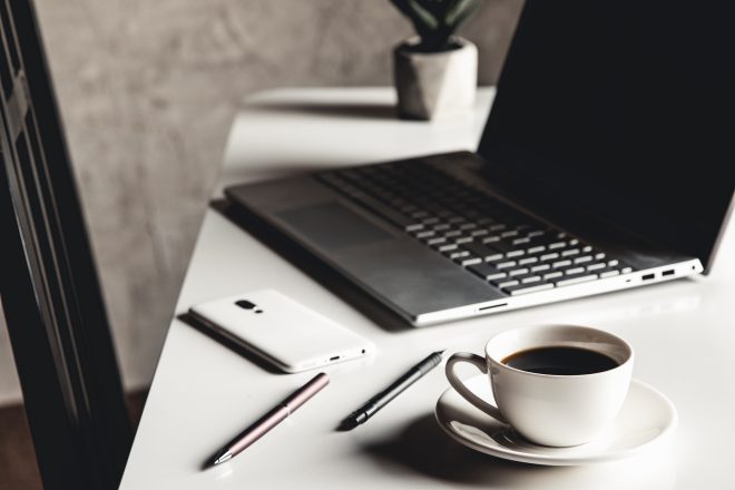 Business man using laptop computer with pen glasses and cup of hot coffee