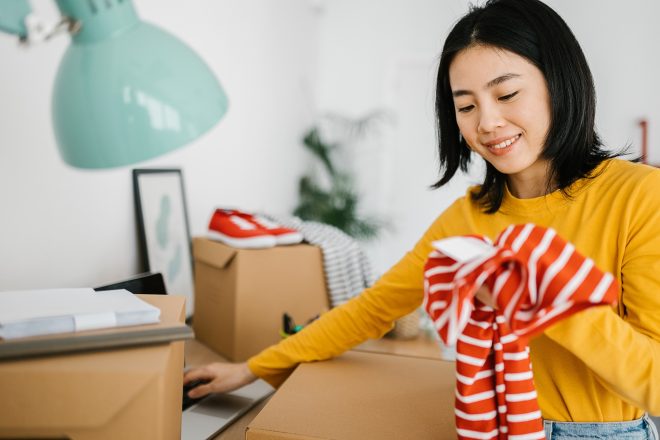 Female young small business owner selling clothes online while working at home.