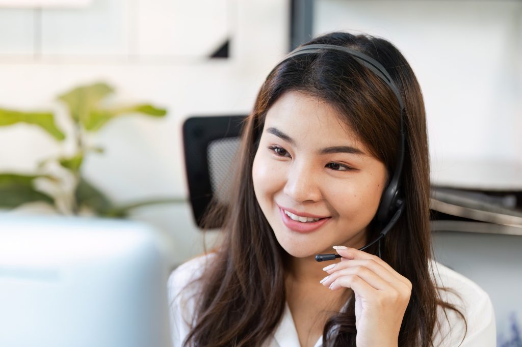 Friendly Female Customer Service Representative with Headset Working in Modern Office Environment