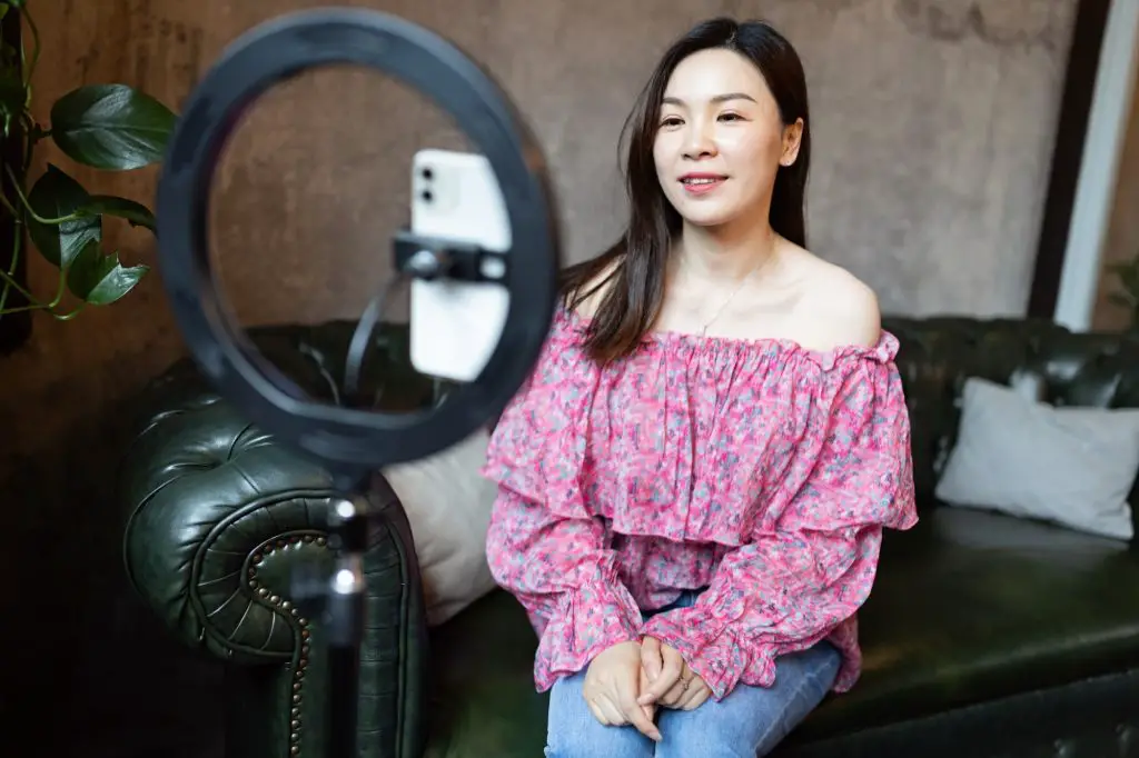 Happy young asian woman influencer using technology in cafeteria or studio