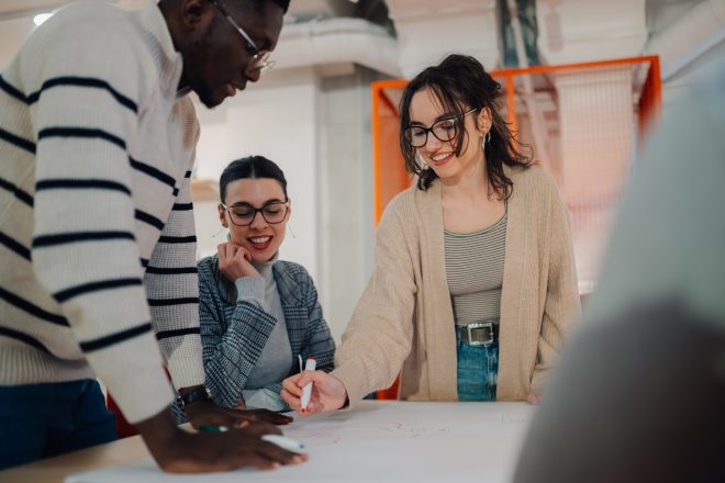 Startup team brainstorming and discussing business ideas on paper in office meeting