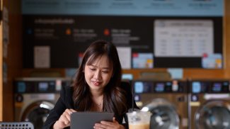 Woman sitting in laundry shop using digital tablet computer