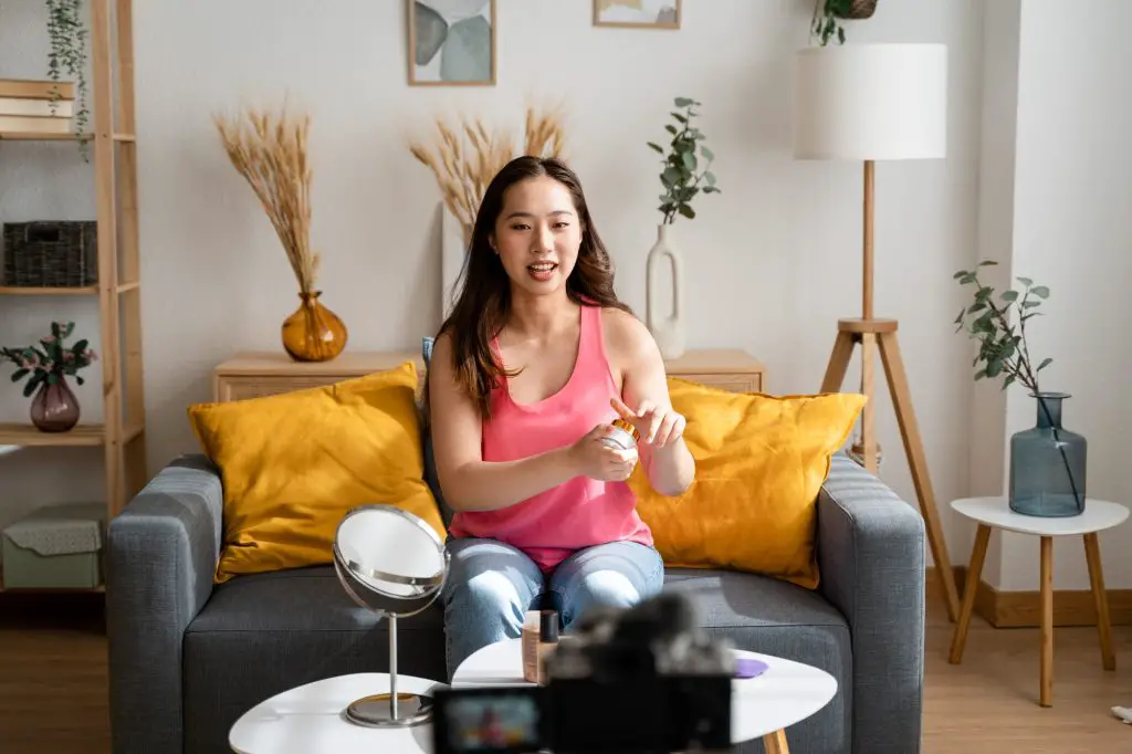 Woman sitting in living room recording a video tutorial for her social media.