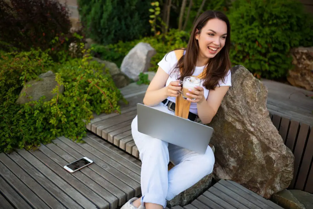 young business woman drinking coffee and working freelance on the street
